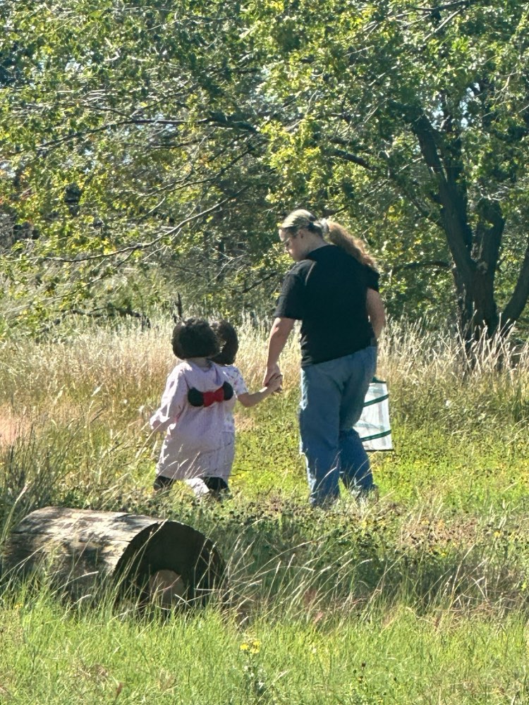 A teacher and a young student walking through a meadow